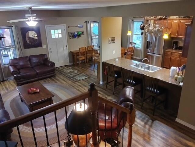 living room with wood finished floors, a ceiling fan, and baseboards