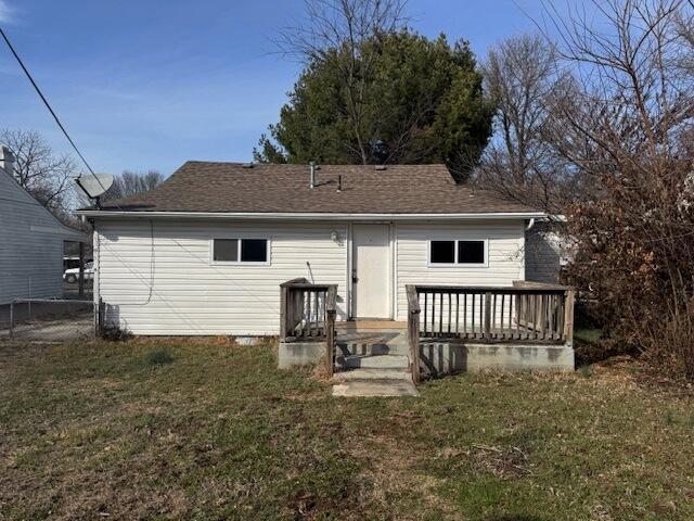 back of house with a shingled roof, a yard, and a wooden deck