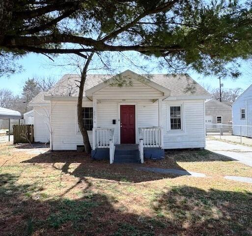 view of front of home featuring a front yard, covered porch, and fence