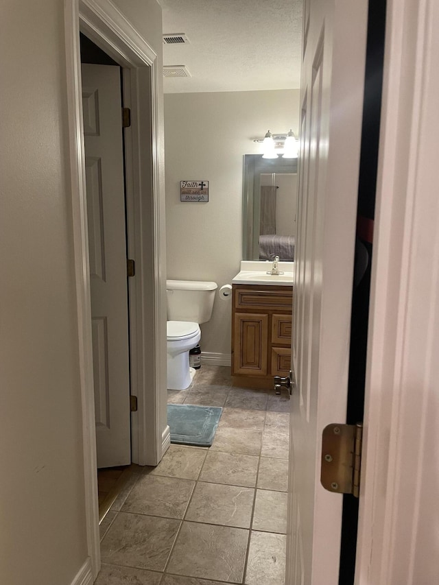 bathroom with visible vents, vanity, toilet, and tile patterned floors