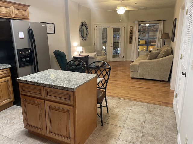 kitchen featuring a breakfast bar, brown cabinetry, light tile patterned floors, and open floor plan