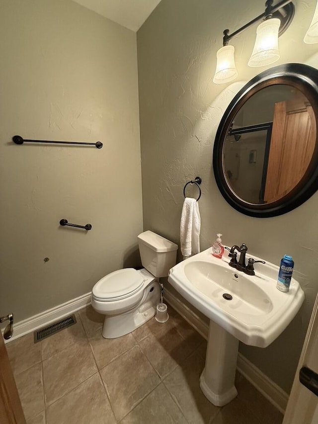 bathroom with visible vents, baseboards, toilet, a textured wall, and tile patterned floors