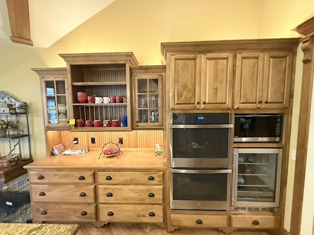 interior space with lofted ceiling, appliances with stainless steel finishes, and beverage cooler