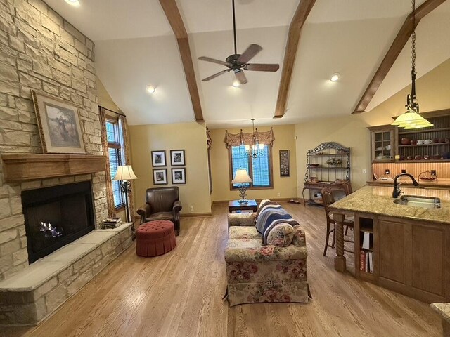 living room featuring beam ceiling, plenty of natural light, a fireplace, and light wood finished floors