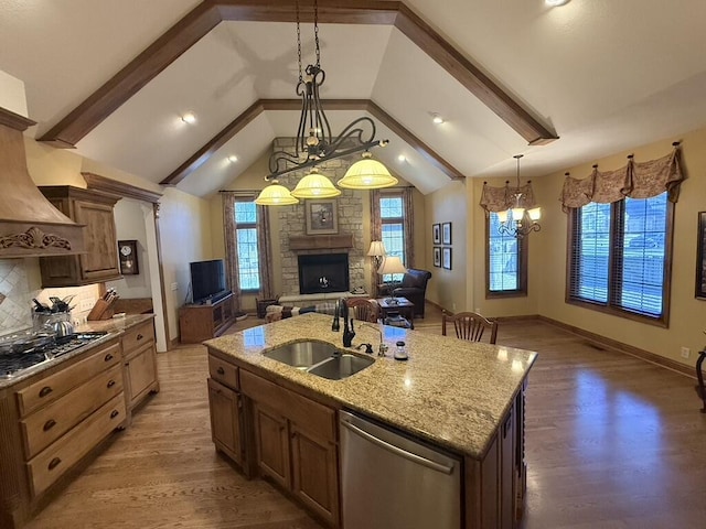 kitchen featuring open floor plan, lofted ceiling, appliances with stainless steel finishes, wood finished floors, and a sink