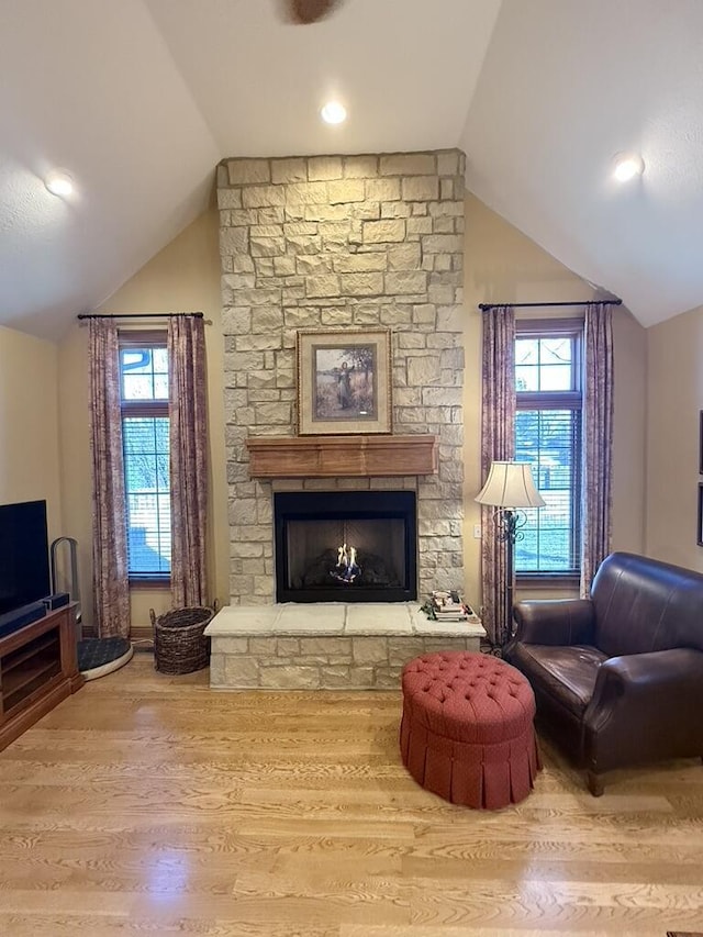 living area featuring a fireplace, vaulted ceiling, and wood finished floors