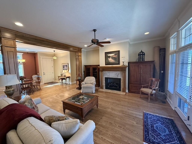 living area with crown molding, baseboards, recessed lighting, a fireplace, and wood finished floors