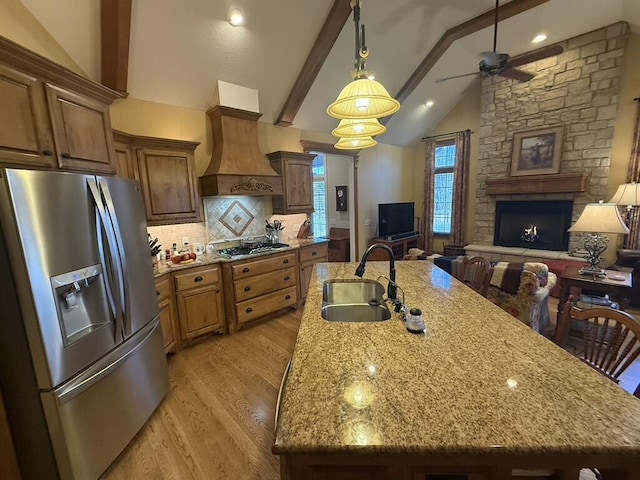 kitchen featuring custom exhaust hood, lofted ceiling with beams, a sink, stainless steel appliances, and open floor plan