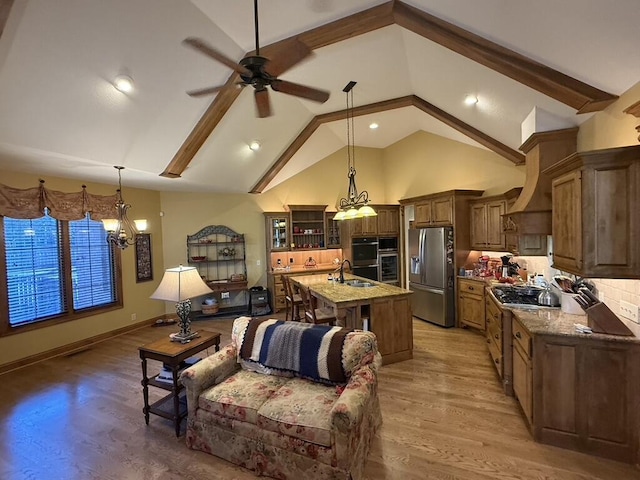 kitchen with light wood finished floors, a center island with sink, stainless steel fridge, and a sink