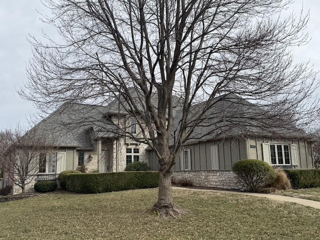 view of front of property with a front lawn, board and batten siding, and stone siding