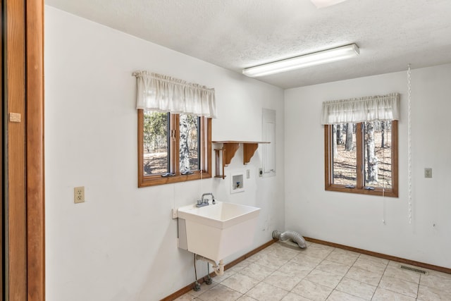 laundry room featuring a textured ceiling, hookup for a washing machine, laundry area, visible vents, and baseboards