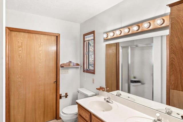 bathroom with a textured ceiling, toilet, a sink, a shower stall, and double vanity