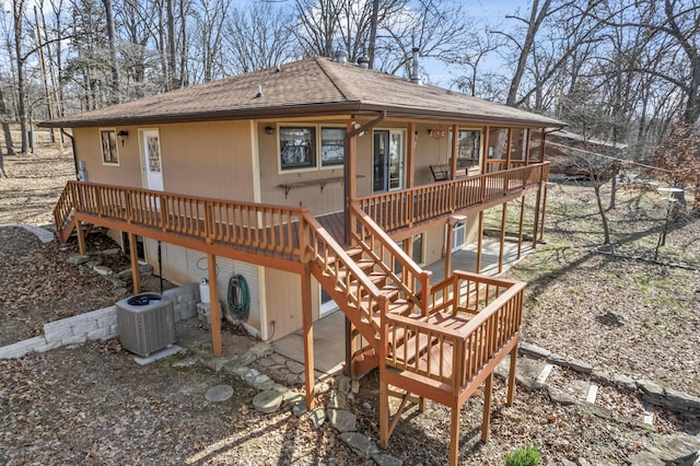 back of property with a patio area, a shingled roof, central AC unit, and a deck