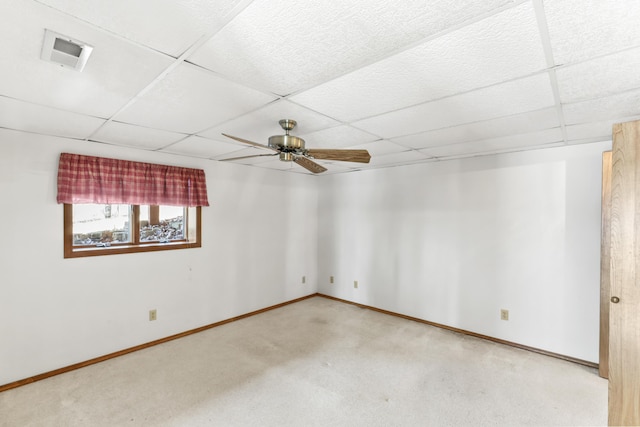 carpeted spare room with baseboards, a drop ceiling, visible vents, and a ceiling fan