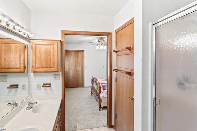 full bathroom with a ceiling fan, a stall shower, a sink, and double vanity