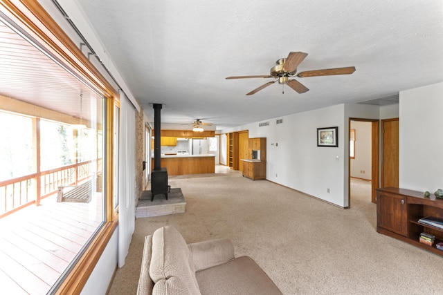 24311 Raintree Ln, Shell Knob, MO 65747 - unfurnished living room featuring ceiling fan, a wood stove, and light colored carpet