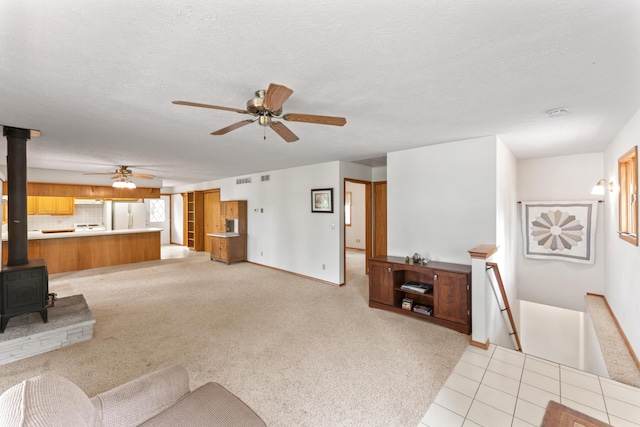 24311 Raintree Ln, Shell Knob, MO 65747 - unfurnished living room with a wood stove, ceiling fan, baseboards, a textured ceiling, and light carpet