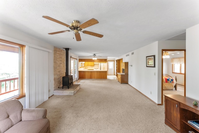 24311 Raintree Ln, Shell Knob, MO 65747 - living room with a wood stove, a ceiling fan, light colored carpet, and baseboards