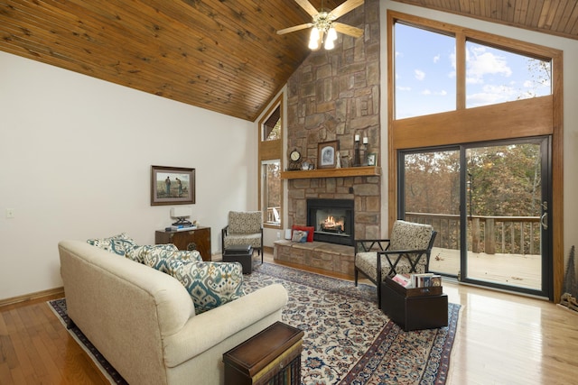 living room featuring high vaulted ceiling, a stone fireplace, wooden ceiling, hardwood / wood-style flooring, and baseboards