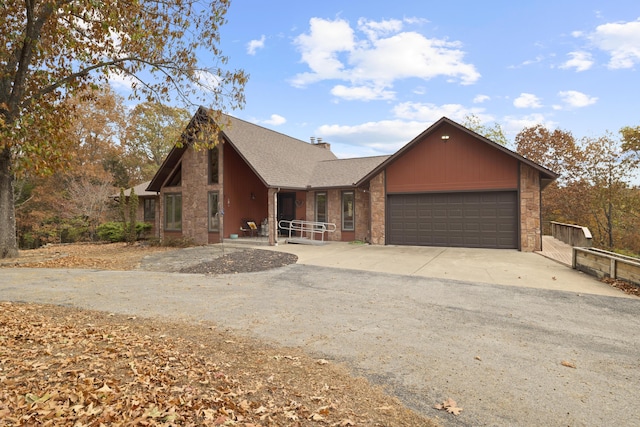 view of front of house featuring driveway, a garage, a chimney, roof with shingles, and brick siding