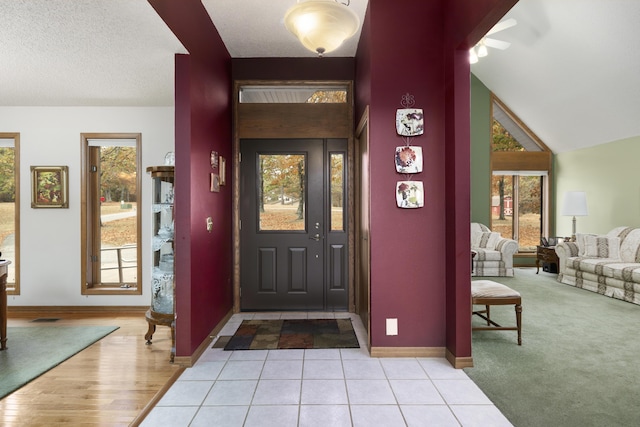 entryway with lofted ceiling, tile patterned flooring, visible vents, and baseboards