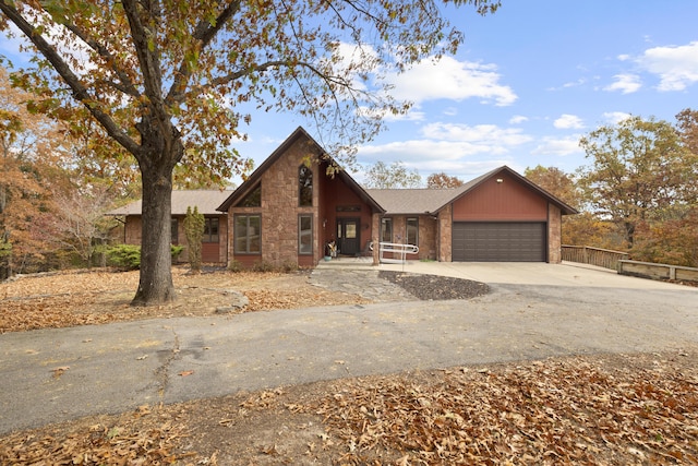 rustic home featuring concrete driveway, brick siding, an attached garage, and fence