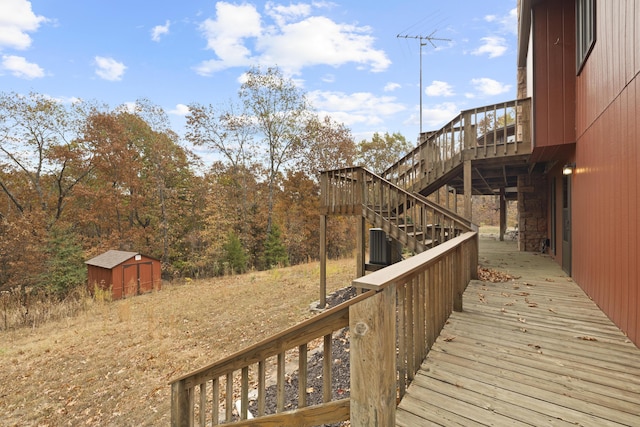 wooden terrace featuring a storage unit, stairway, and an outdoor structure