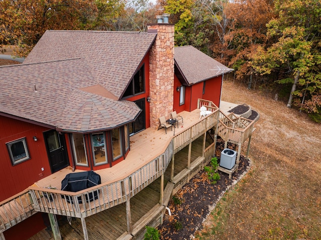 exterior space with roof with shingles, a chimney, a wooden deck, and central air condition unit