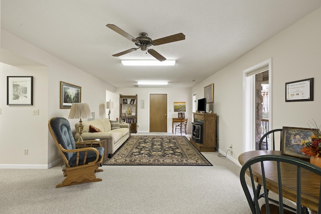 carpeted living area with a fireplace, a textured ceiling, baseboards, and ceiling fan