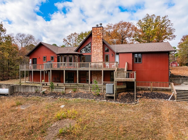 back of property featuring a deck, a shingled roof, and a chimney