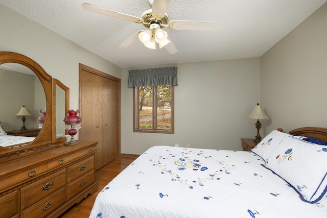 bedroom with a ceiling fan, a closet, light wood-style flooring, and a textured ceiling