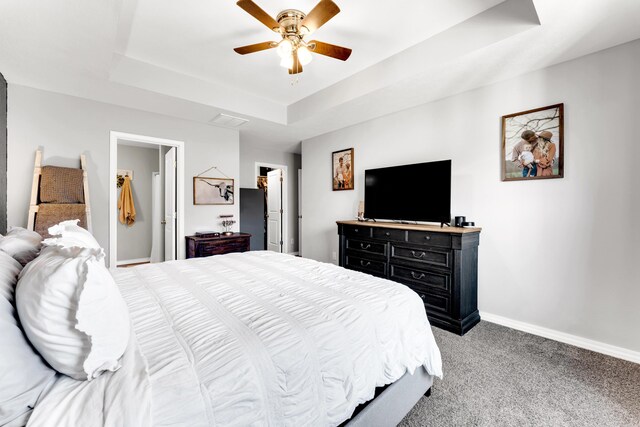 carpeted bedroom featuring baseboards, visible vents, a ceiling fan, a spacious closet, and a tray ceiling