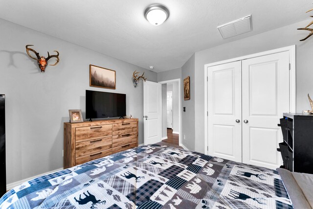 bedroom with baseboards, visible vents, and a closet