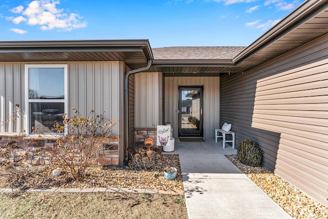 property entrance featuring stone siding, board and batten siding, and roof with shingles