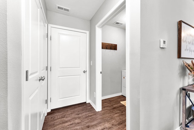 hallway featuring dark wood finished floors, visible vents, and baseboards