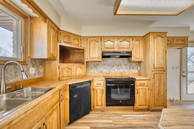 kitchen with black appliances, under cabinet range hood, light countertops, and a sink