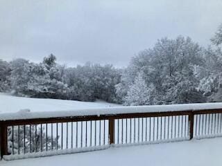 snow covered deck featuring a wooded view