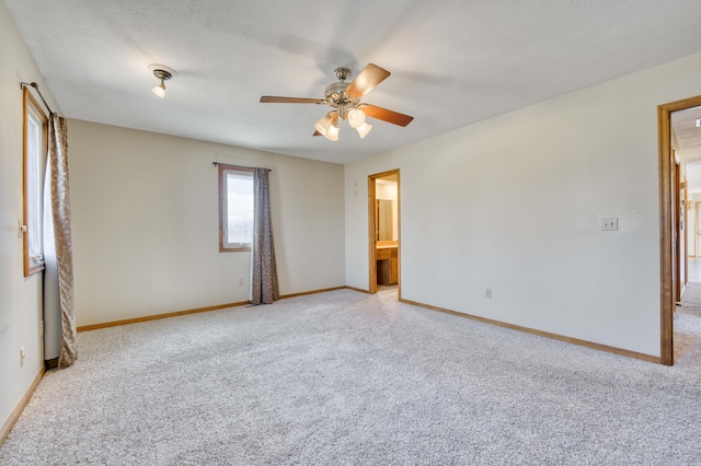 carpeted empty room with baseboards and a ceiling fan