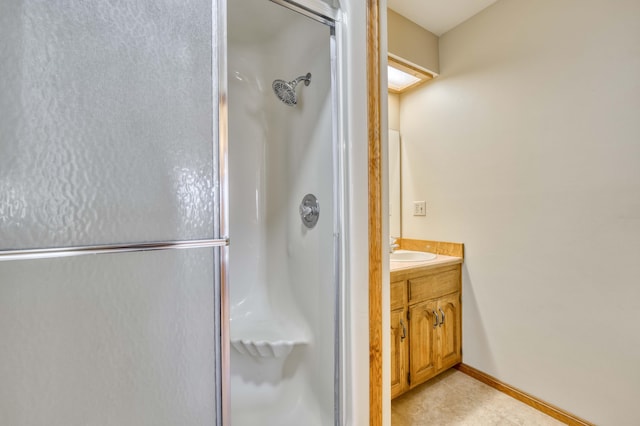 full bath with a stall shower, vanity, and baseboards