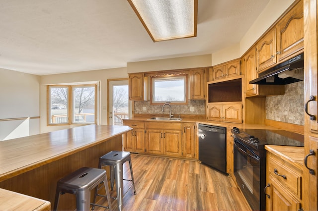 kitchen with black appliances, a sink, a wealth of natural light, and under cabinet range hood