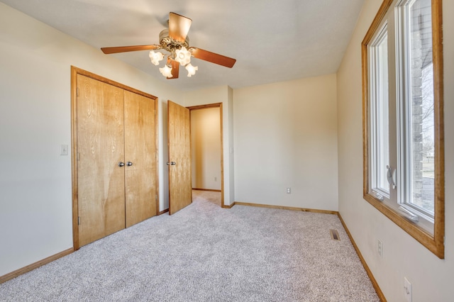 unfurnished bedroom featuring light carpet, visible vents, a ceiling fan, baseboards, and a closet