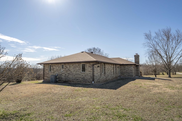 view of home's exterior featuring a yard, brick siding, a chimney, and cooling unit