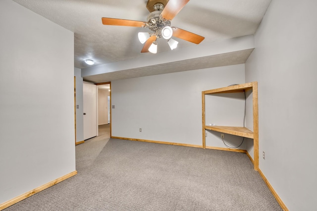 carpeted empty room featuring a textured ceiling, baseboards, and a ceiling fan