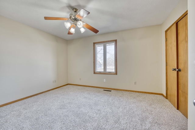 unfurnished bedroom featuring carpet floors, a closet, visible vents, a ceiling fan, and baseboards