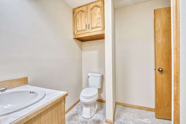 half bathroom with vanity, toilet, and baseboards