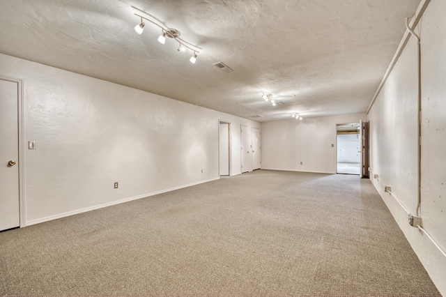 carpeted empty room with baseboards, a textured ceiling, and a textured wall