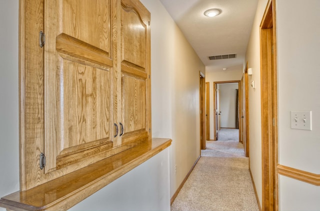 hall with visible vents, light carpet, and baseboards