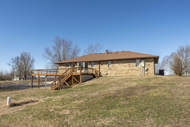 back of house with brick siding, a yard, central AC unit, a deck, and stairs