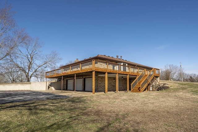 rear view of property with a garage, driveway, stairway, a lawn, and a wooden deck