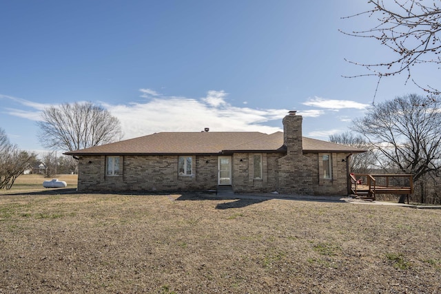 rear view of property featuring roof with shingles, a chimney, a lawn, and brick siding